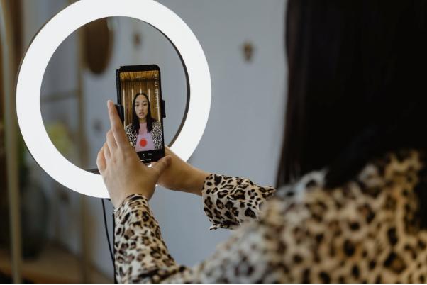 Une créatrice de contenu tourne une vidéo TikTok avec son smartphone et une lampe annulaire