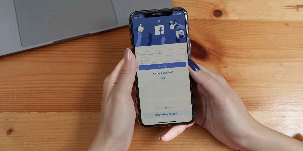 Logging into Facebook on a smartphone next to a laptop