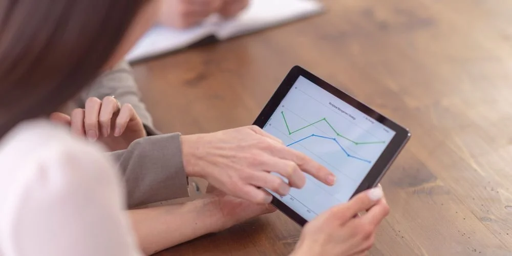 People are analyzing a line graph on a tablet