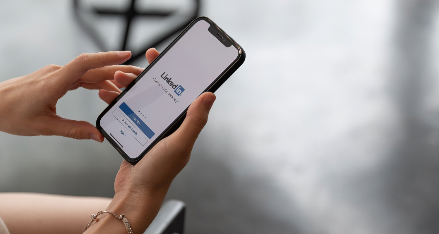 A person is holding a smartphone with the LinkedIn app open