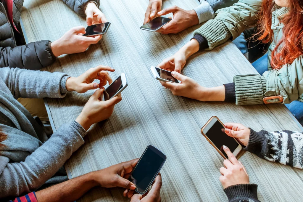 Several people are using smartphones at a table