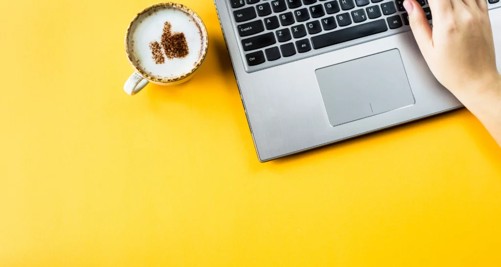 Un ordinateur portable et une tasse à café sur fond jaune