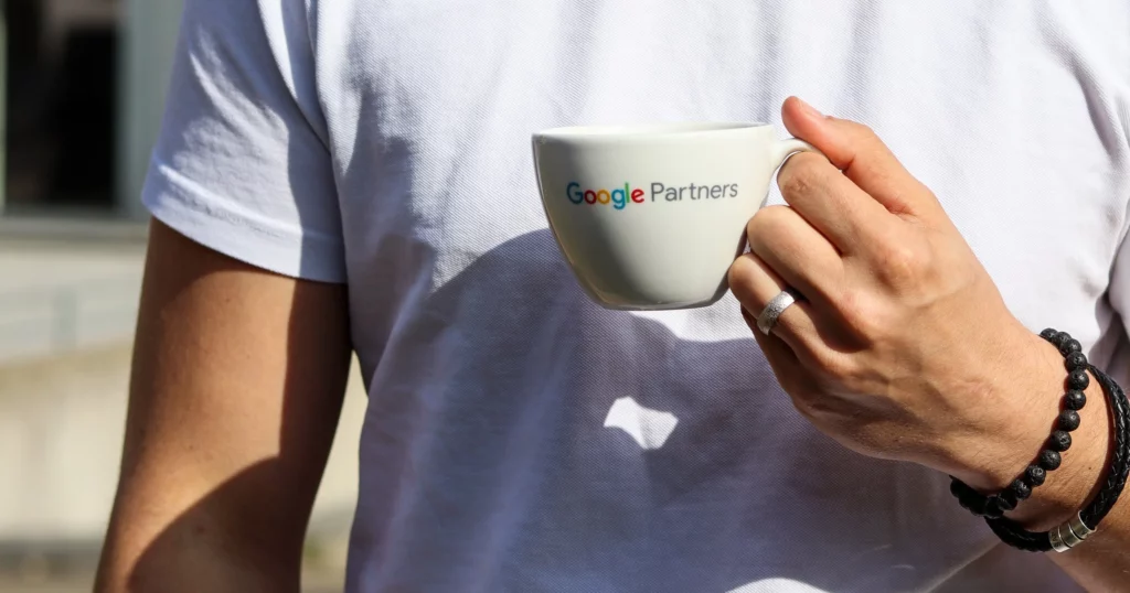 A person is holding a cup with the Google Partners logo on it