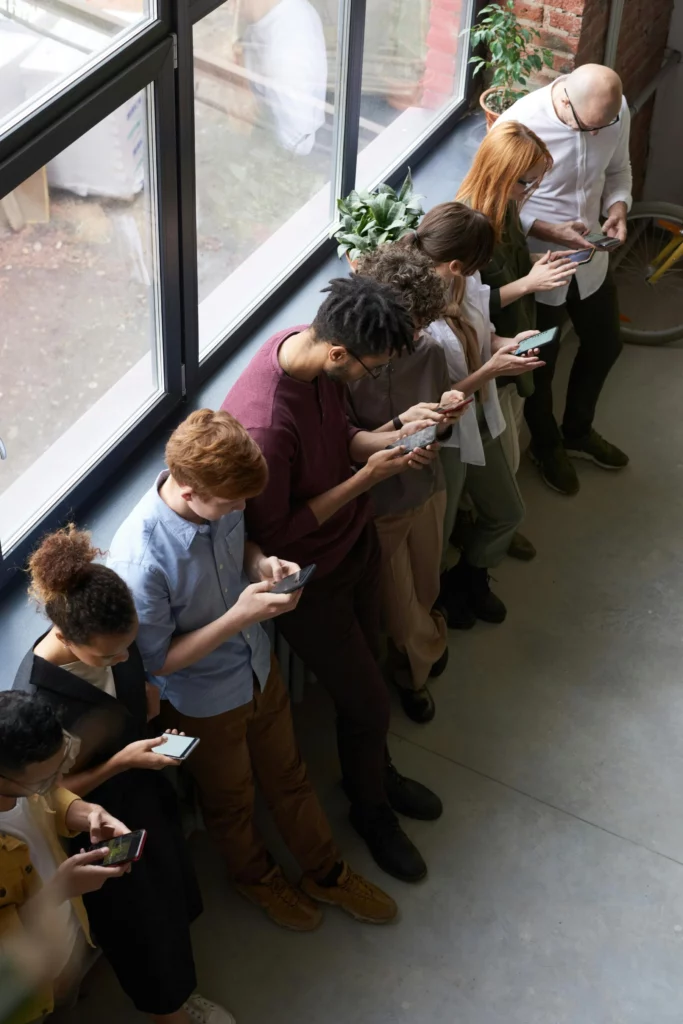 A group of people of various backgrounds are looking at their smartphones