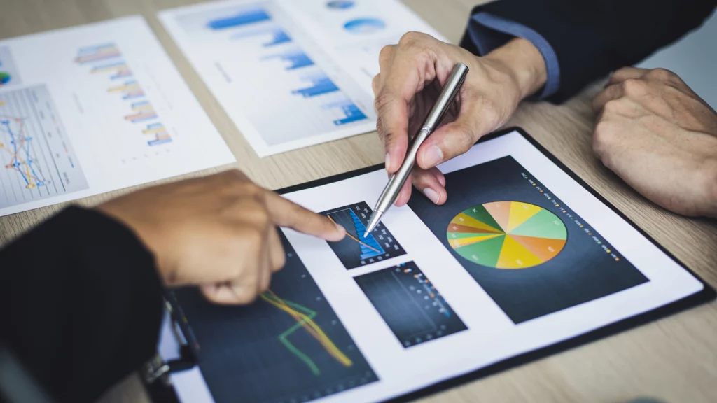Two people are analyzing charts on a tablet