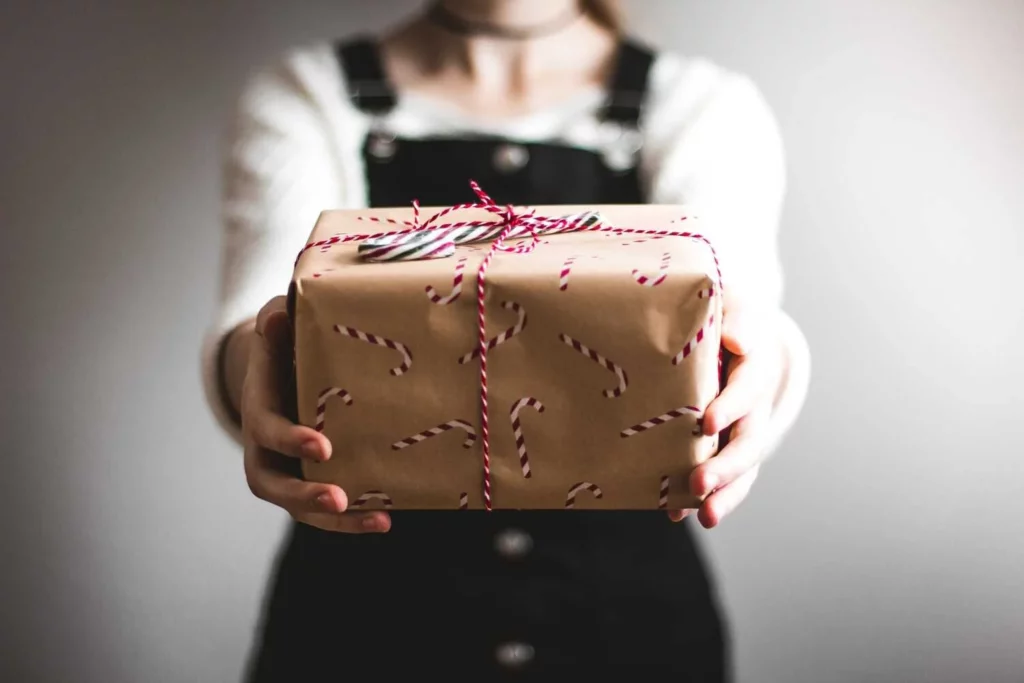 A person holds a wrapped Christmas present up to the camera