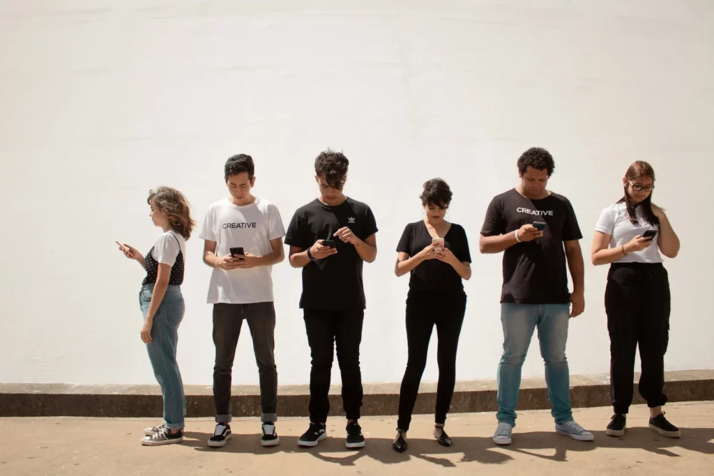 Junge Menschen nutzen Smartphones vor einer hellen Wand