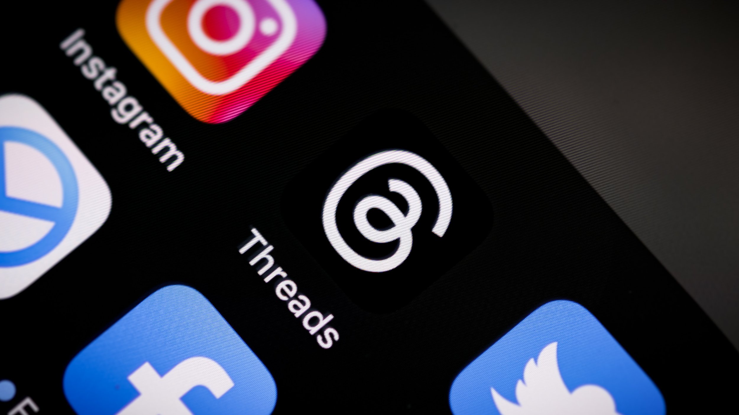 The Threads app icon next to Instagram, Facebook, and X on a smartphone