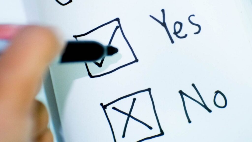 Hand marks a yes/no checklist