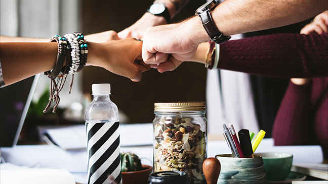 Several people touch their fists together as a symbol of cooperation