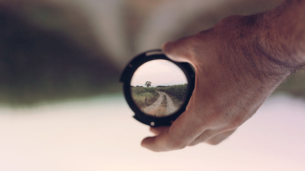 A hand holds a compass, looking down a path
