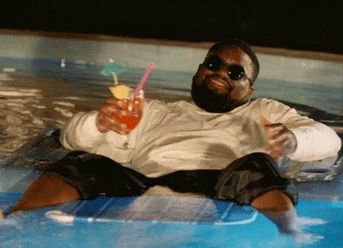 Un homme se détend sur un matelas gonflable dans la piscine, un verre à la main.
