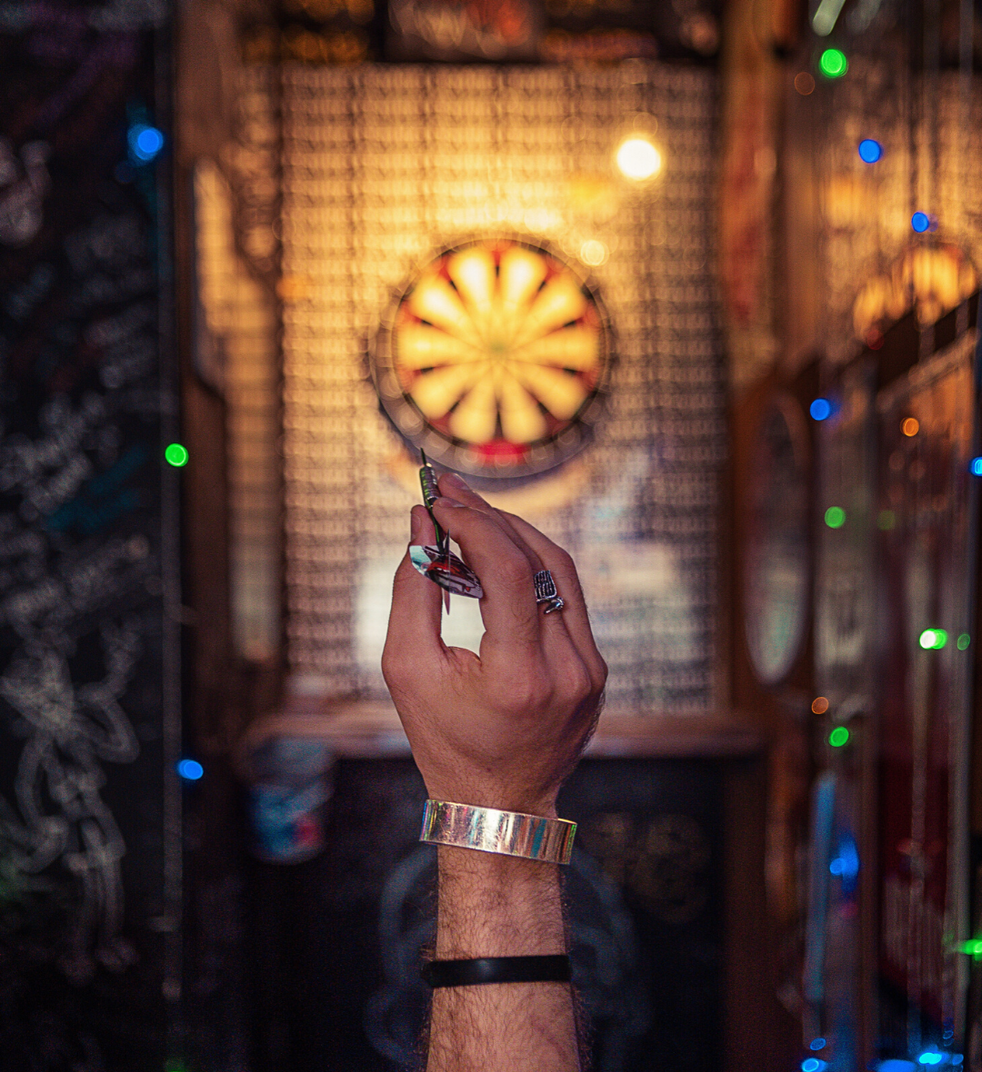 A hand throws a dart at a glowing dartboard