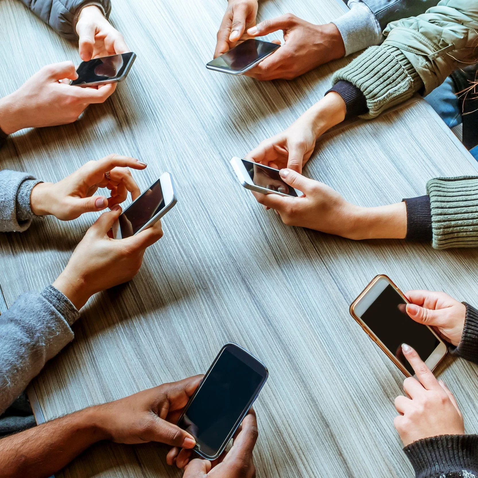 A group of people are using smartphones together at a table