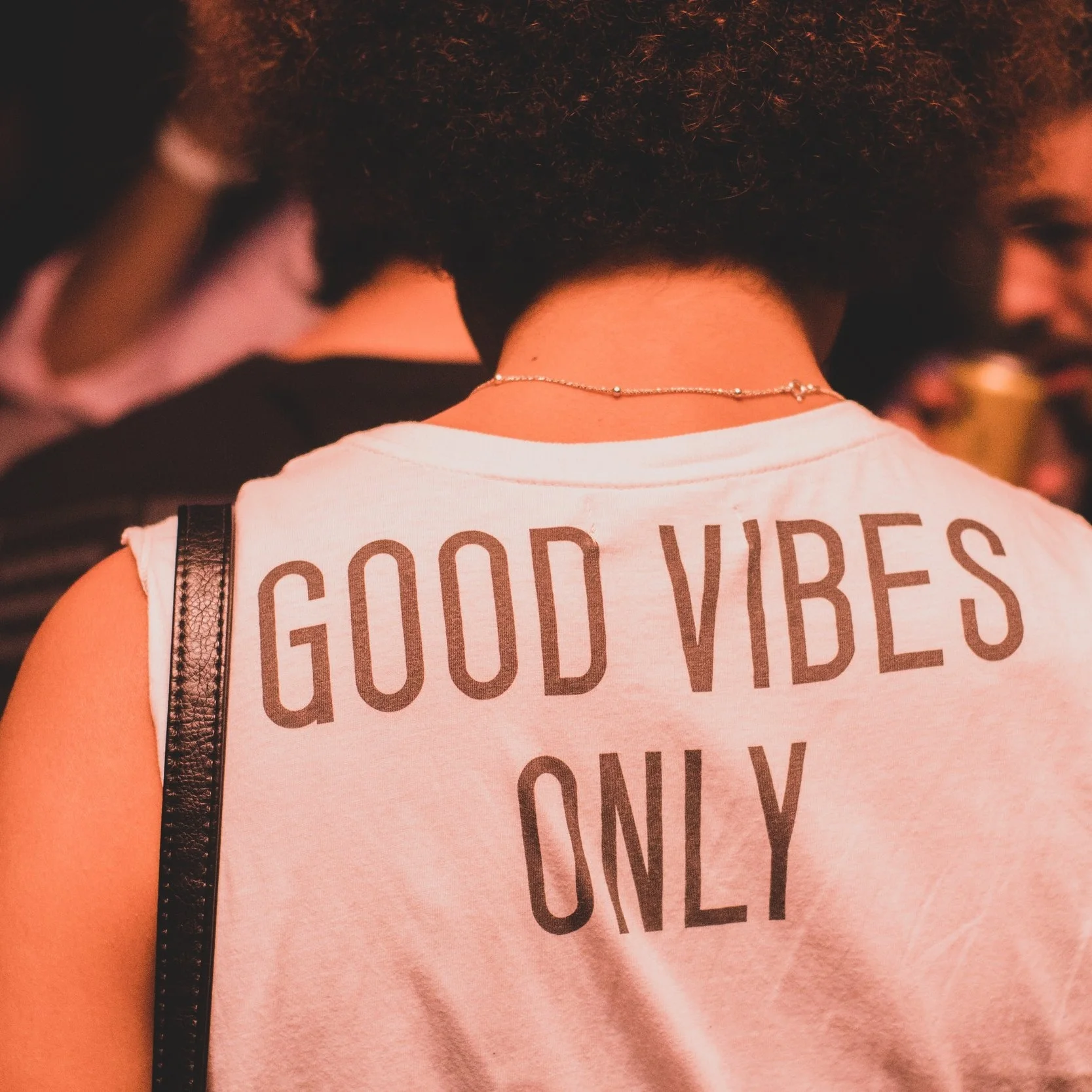 A person is wearing a top with the words "Good Vibes Only" on it