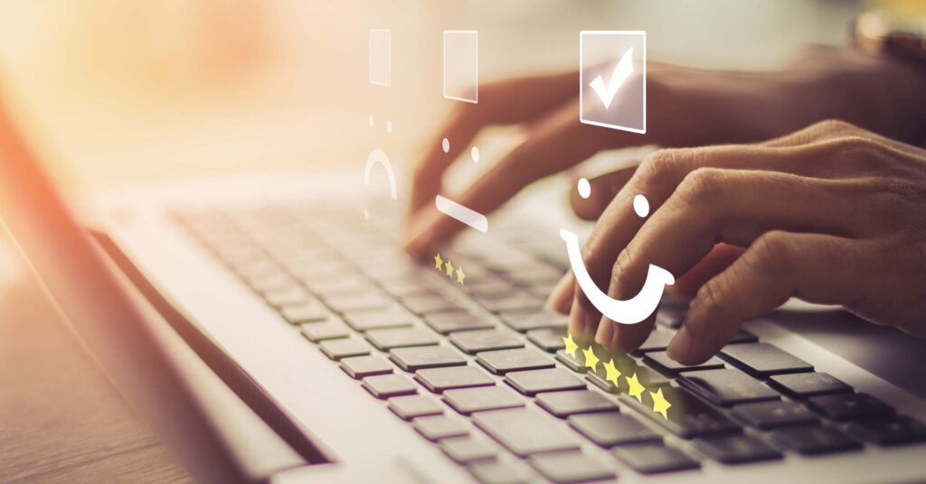 Hände tippen auf einem Laptop neben Symbolen für gute und schlechte Online-Bewertungen.