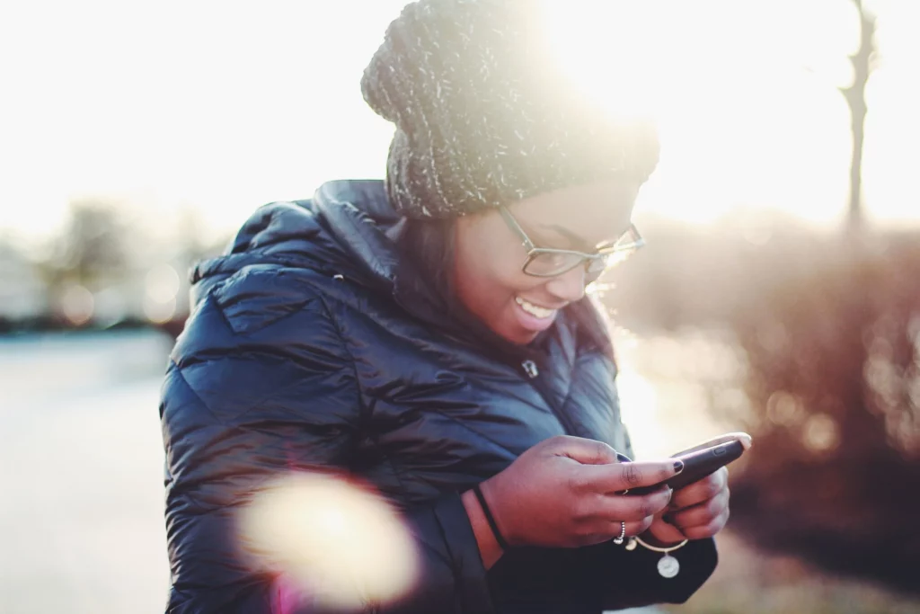 A woman is looking at her smartphone outdoors.