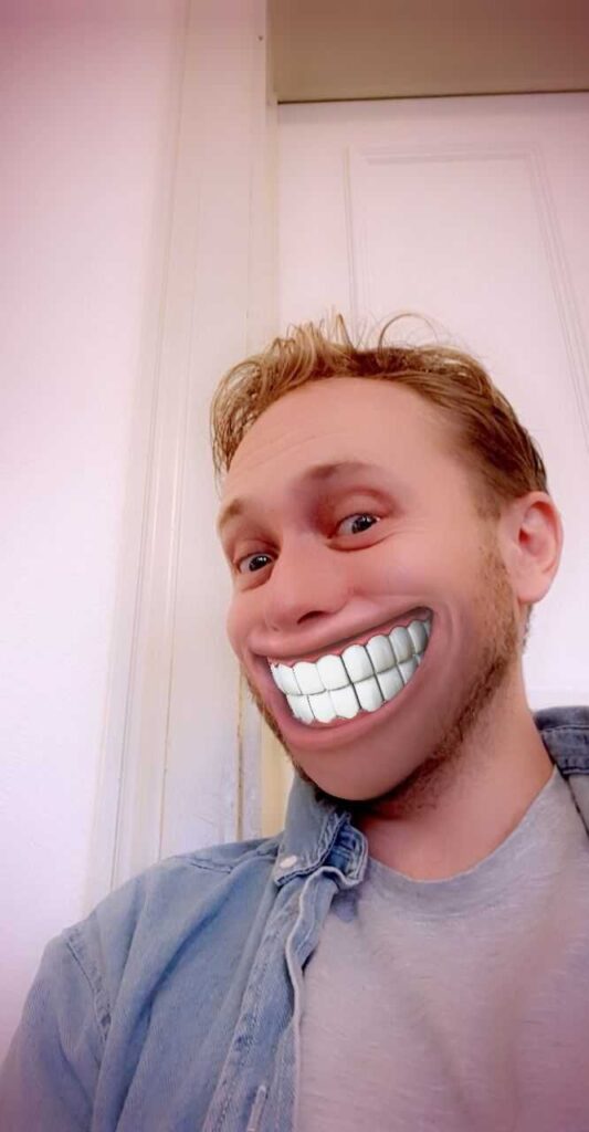 Man wearing a Snapchat filter that makes his smile look exaggeratedly wide