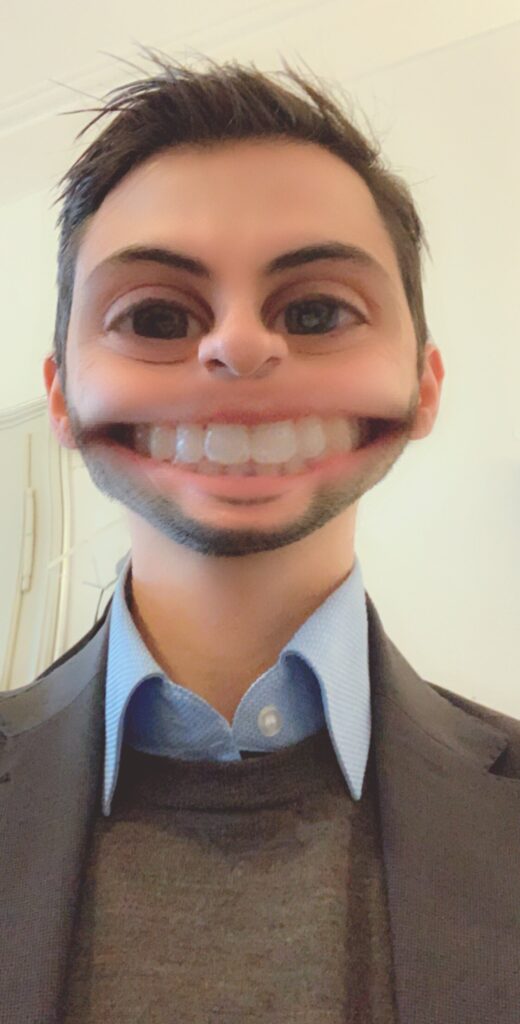 Man in a suit with the "big eyes" and "smile" Snapchat filters