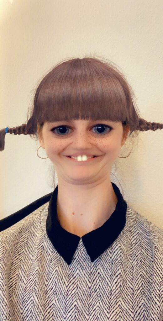 Woman with braids, freckles, and a Snapchat filter that makes her teeth look gapped
