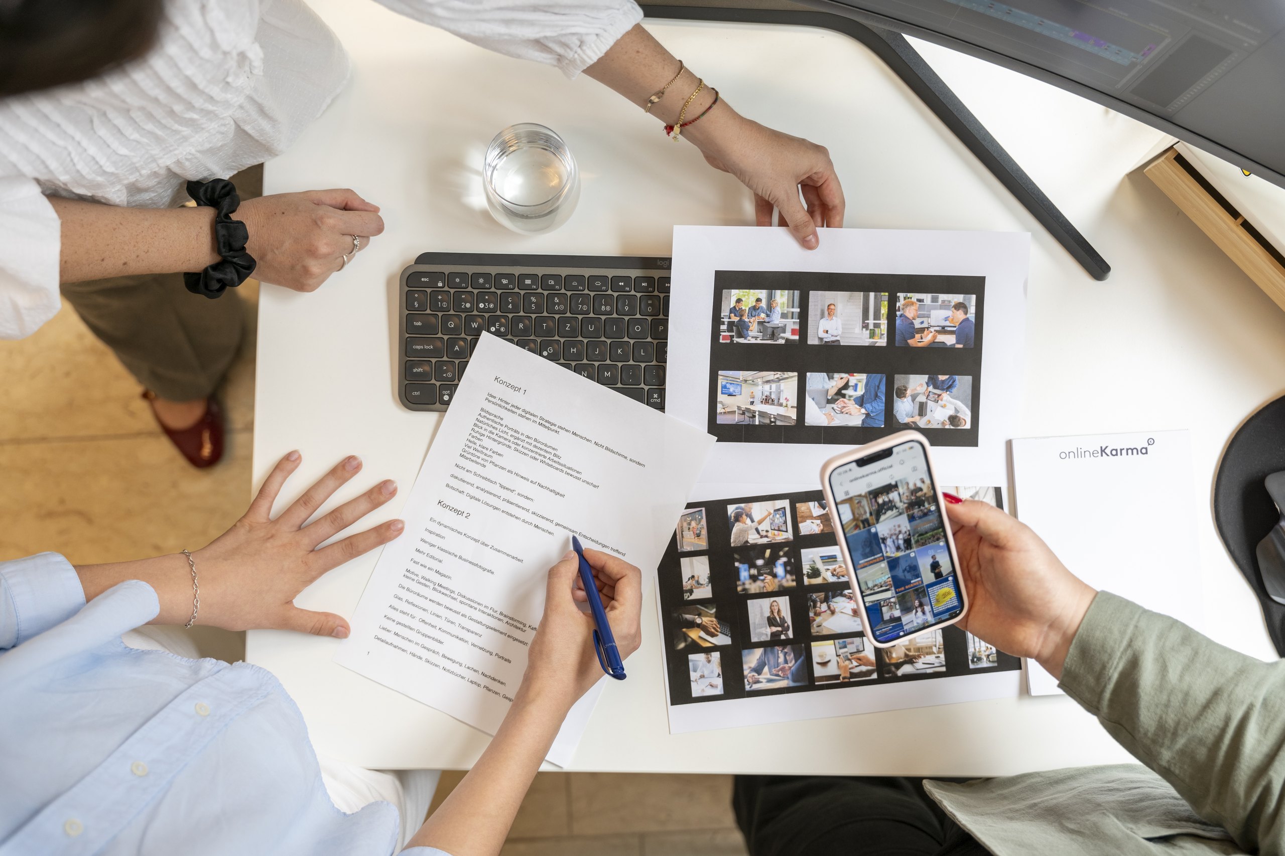 Three onlineKarma team members plan content using printouts and a smartphone