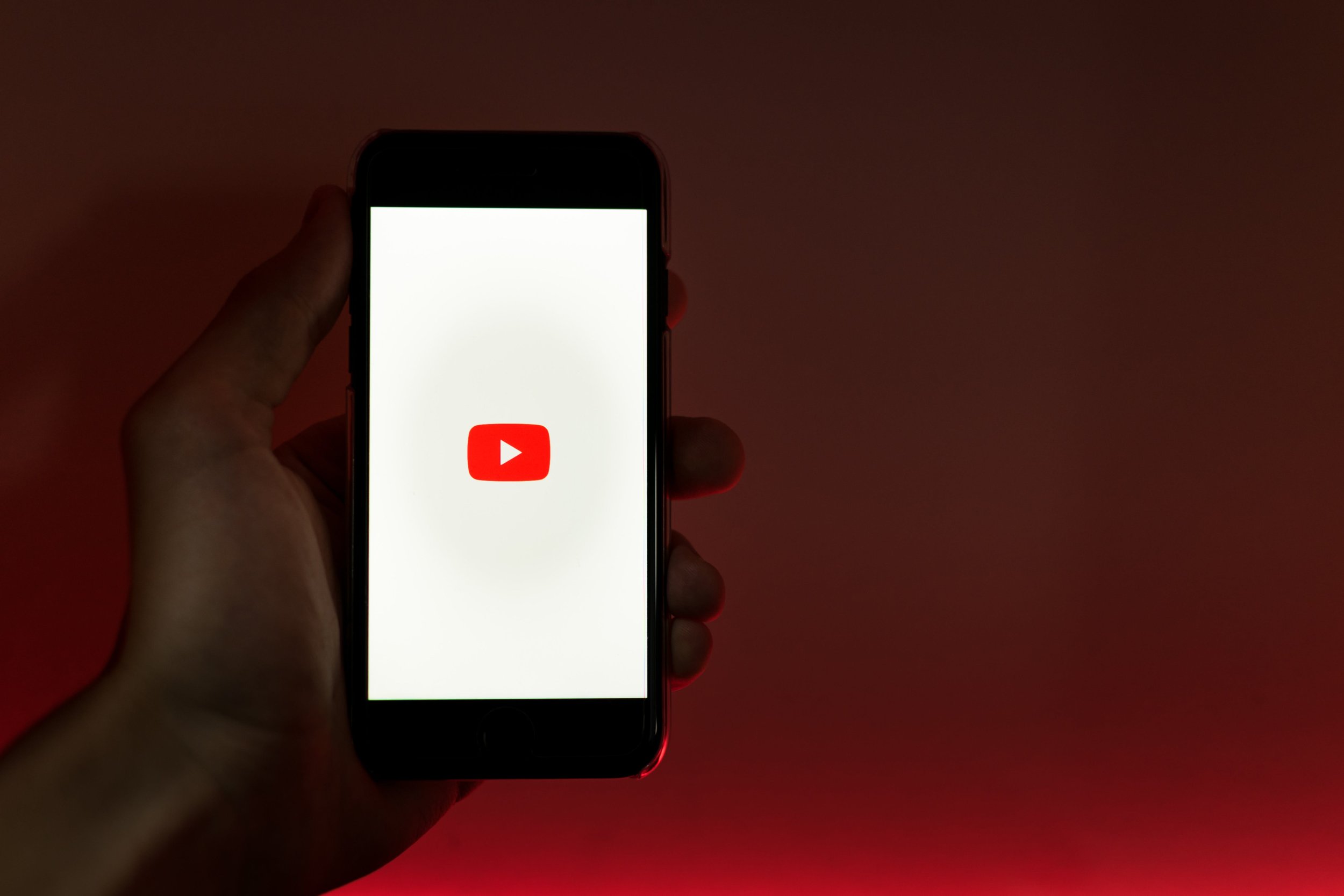 YouTube app on a smartphone against a red background