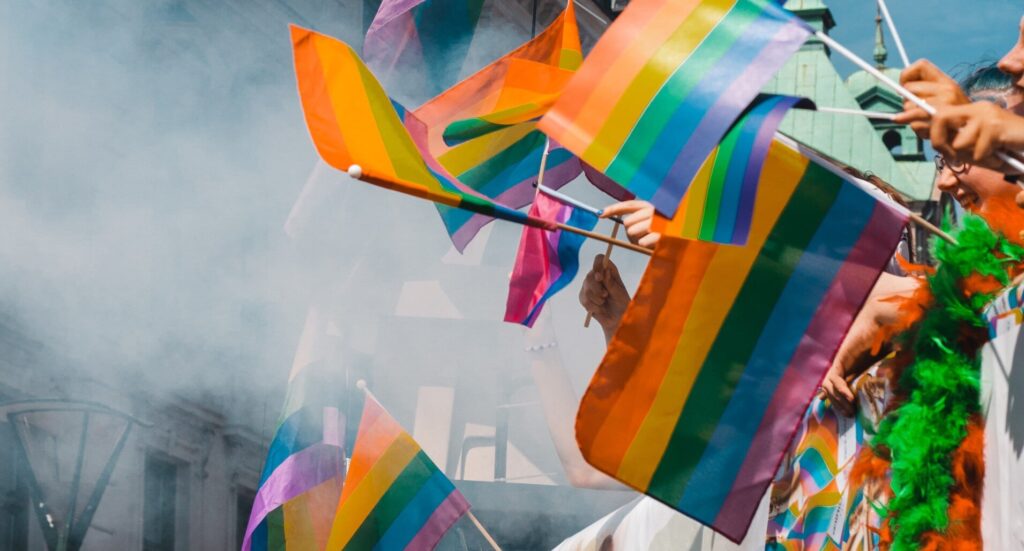 Des personnes brandissent des drapeaux arc-en-ciel lors d'un événement de la Pride.