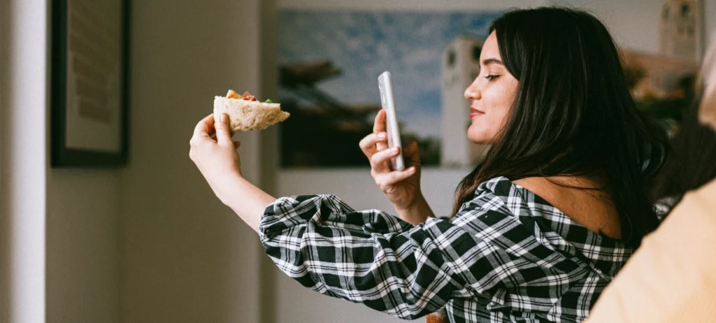 A woman takes a photo of her food for a social media story