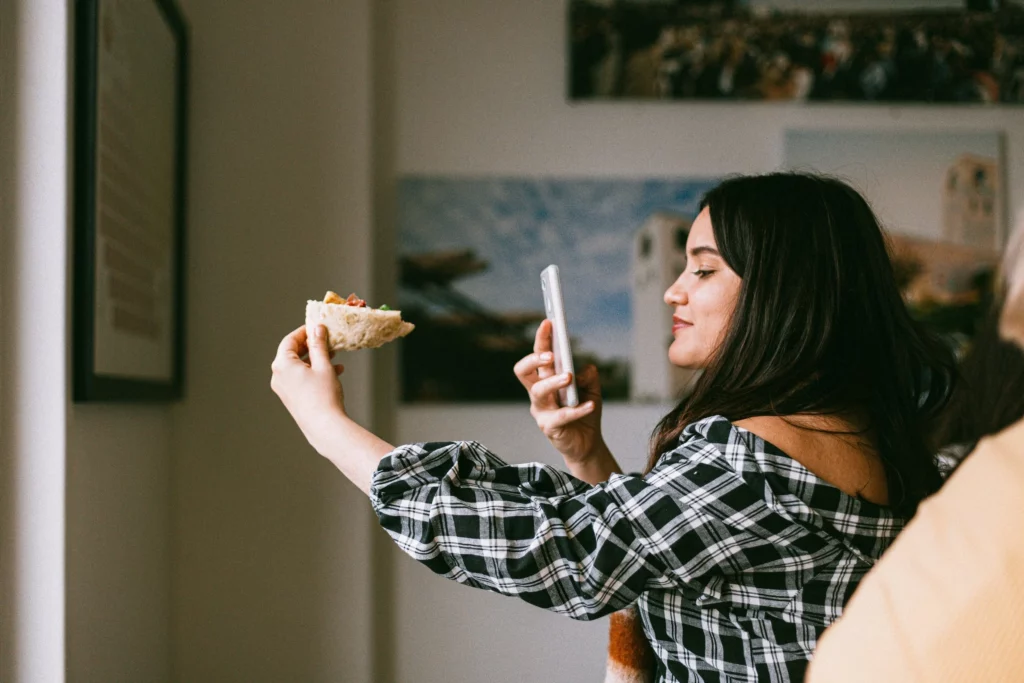 Frau fotografiert ihr Essen mit einem Smartphone