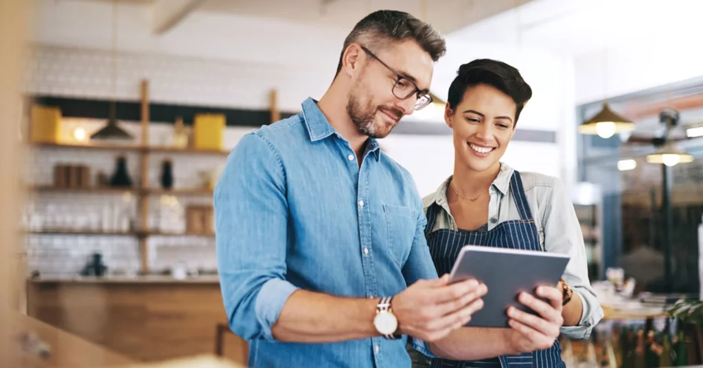 A man and a woman are looking at a tablet together in a small business