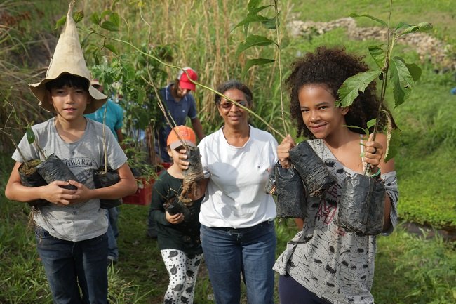 Children and adults with tree seedlings during a reforestation project